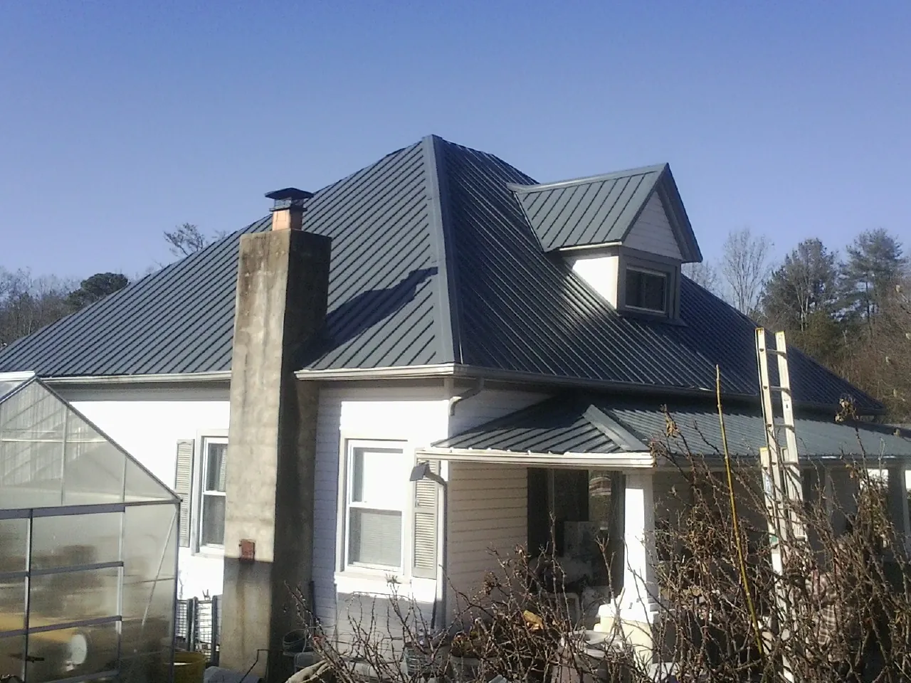 Dark blue standing seam metal roof on a white farmhouse with dormer — Slate & Tile Roof Repair by Roofing Brothers in Rebuck