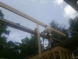 Carpenter setting a ridge beam over a new addition frame in Rebuck