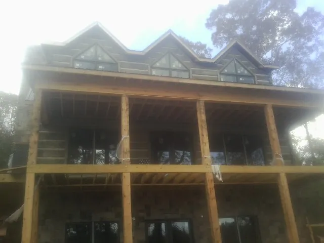 Dormers and porch framing on a large log home under construction — Roof Coating work by our crew in Rebuck