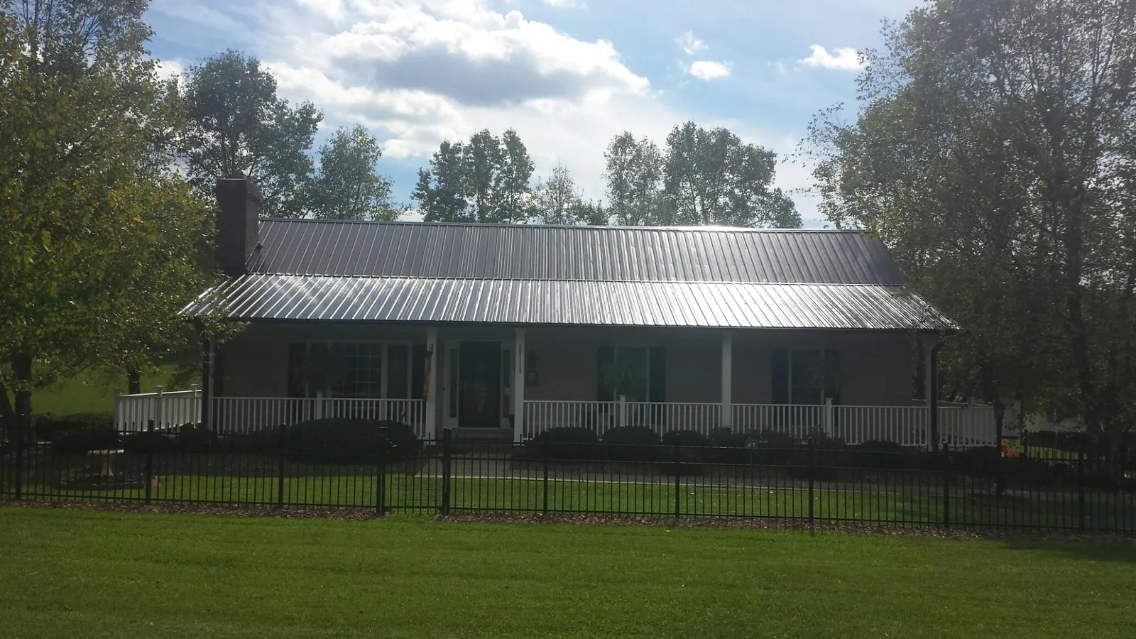 Gray metal roof on a brick ranch with a full width front porch — Gutter Guard Installation work by our crew in Rebuck
