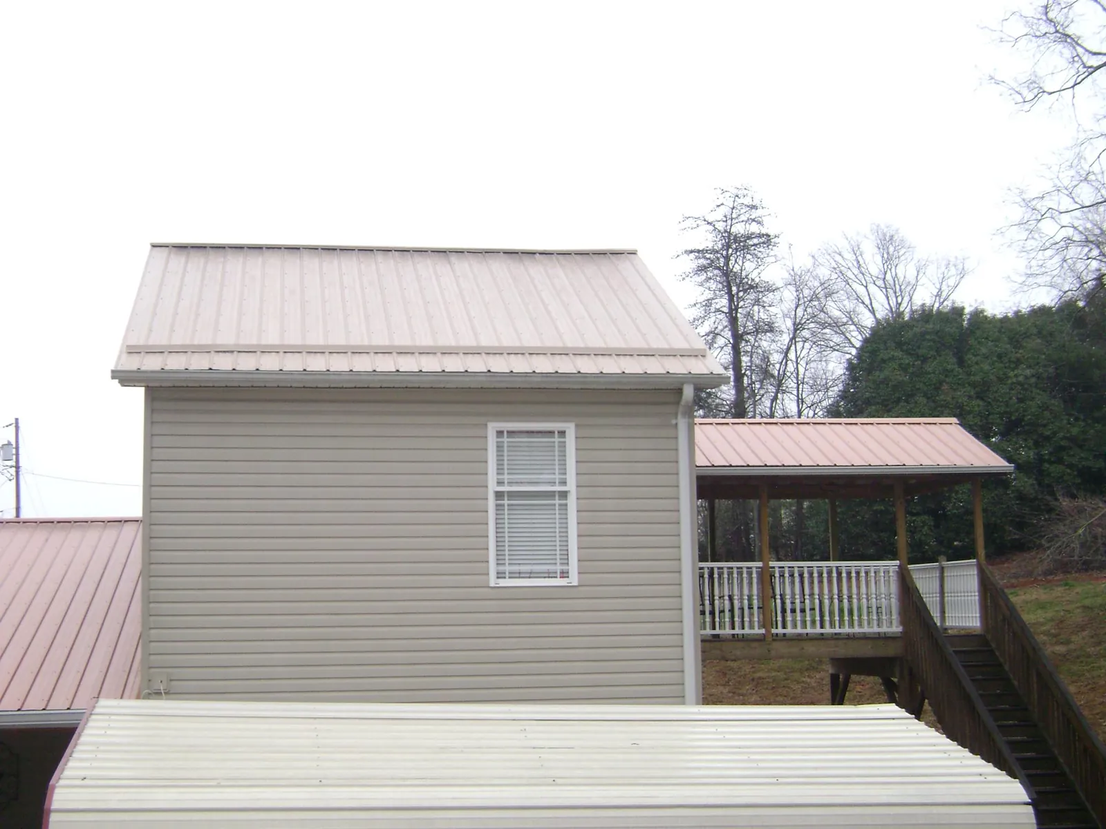 Tan metal roofs on a two story addition and attached porch, from a Roof Replacement job in Rebuck